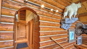 A log cabin interior with a wooden door, a stone fireplace, and a mounted animal head.