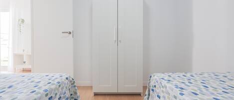 Une chambre avec deux lits, une armoire et une petite table sur laquelle est posée une plante.