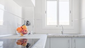A modern kitchen with white cabinetry, a granite countertop, a built-in oven, and a fruit bowl on the counter. - Apt high qualities 2 BR Algaba (La Algaba)