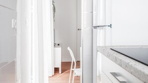 Uma cozinha moderna com armários brancos, bancada de mármore e coifa de aço inoxidável.