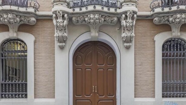 A building facade with ornate architectural details, including a large wooden door and decorative ironwork.
