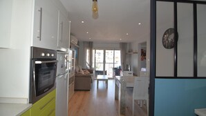 Una cocina moderna con horno empotrado y zona de comedor con mesa y sillas blancas.