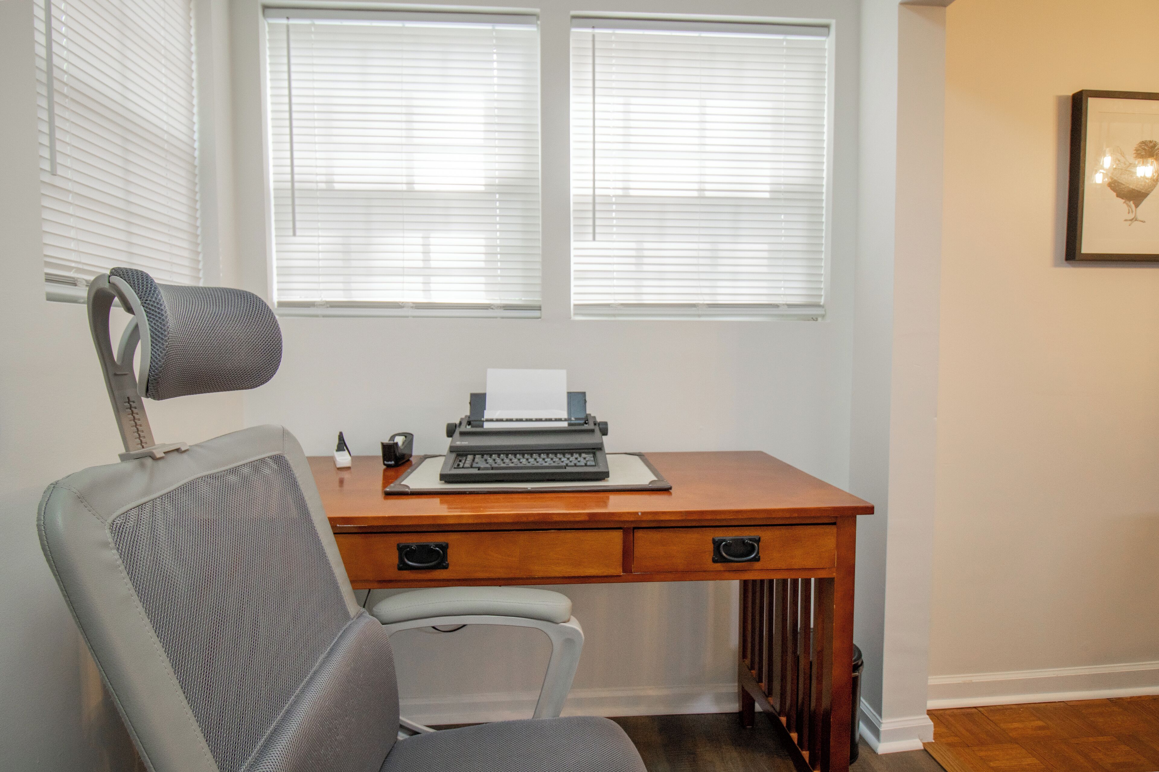 A wooden desk with a typewriter, a chair, and a radiator below.