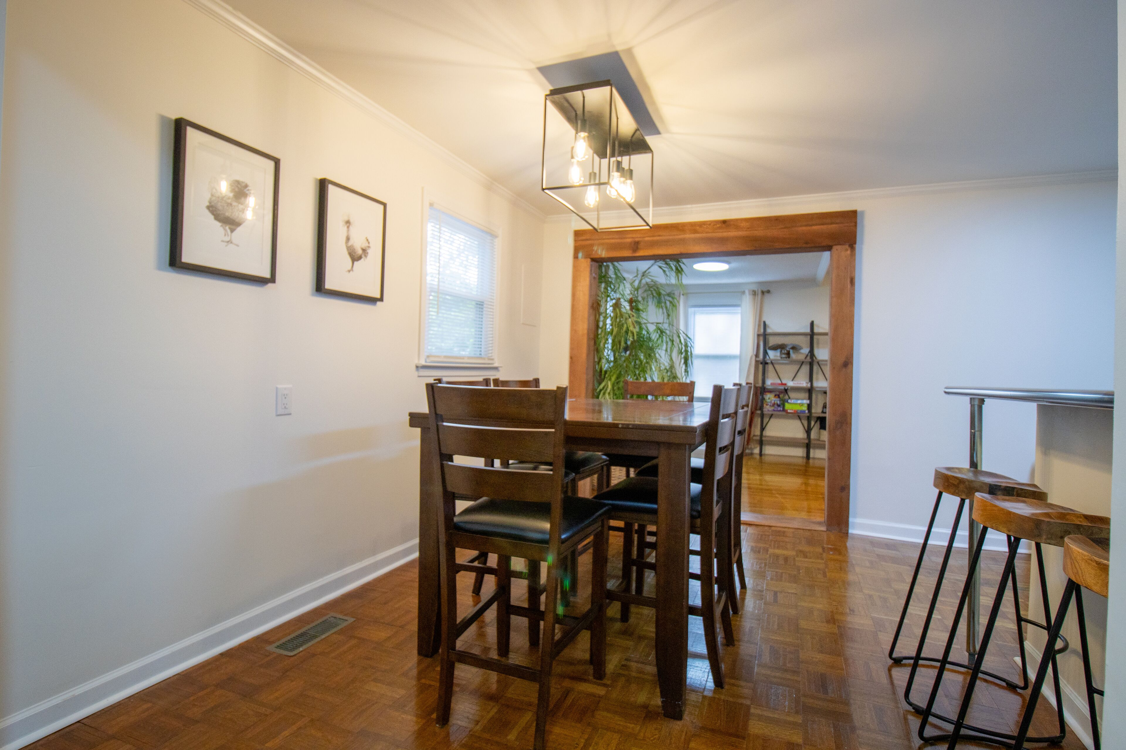 Een eetruimte met een houten tafel en stoelen, kunstwerken aan de wand en een hanglamp.