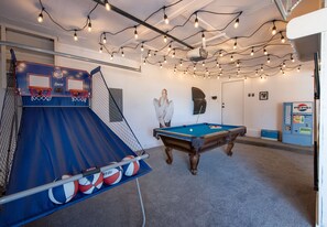 Ein Freizeitraum mit Basketballkorb, Billardtisch und Lichterkette.