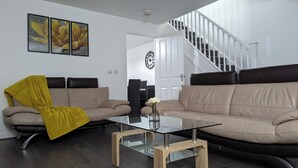 A modern living room with a sofa, coffee table, and a staircase leading to an upper floor. - Burnley Entire House 4-Bedrooms-Sleeps 6-Driveway (Burnley)