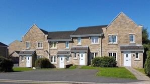 A row of townhouses with a paved driveway and a clear blue sky. - Burnley Entire House 4-Bedrooms-Sleeps 6-Driveway (Burnley)