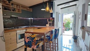A modern kitchen with wooden cabinets, a central island, and bar stools with colorful upholstery. - 2 Bedroom Apartment Sleeps 4 -Free Parking -Garden (Zadar)
