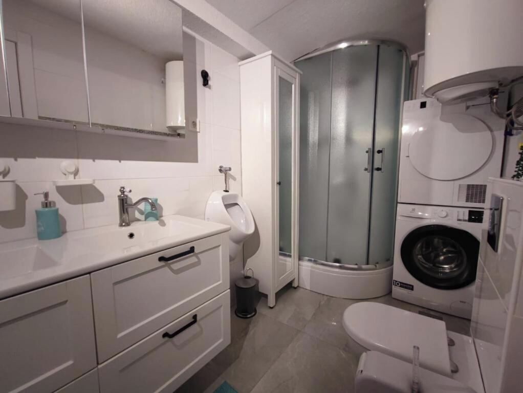 Een kleine badkamer met toilet, wastafel, spiegel en een douchecabine in een hoek.