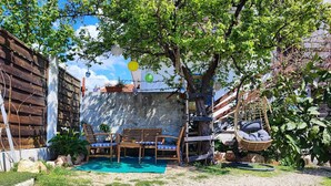 A rustic outdoor seating area with a wooden bench and chairs, surrounded by greenery and a concrete wall. - 2 Bedroom Apartment Sleeps 4 -Free Parking -Garden (Zadar)