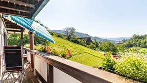 Een balkon met uitzicht op een groen landschap, een stoel en een tafel.