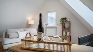 A room with a wooden table, a bottle of Black Best wine, and two wine glasses on a tray. - Apartment "Annele" with Private Terrace & Wi-Fi (Loßburg)