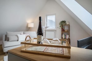 A room with a wooden table, a bottle of Black Best wine, and two wine glasses on a tray. - Apartment "Annele" with Private Terrace & Wi-Fi (Loßburg)