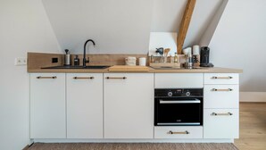 A modern kitchen with a built-in oven, a sink, and a coffee maker. - Apartment "Annele" with Private Terrace & Wi-Fi (Loßburg)
