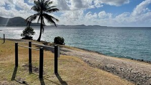 A beach with a palm tree, a wooden fence, and a clear view of the ocean. - Studio privé dans le complexe de Pierre et Vacances (Sainte Luce)