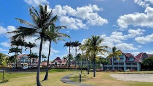 A resort with palm trees, a curved pathway, and buildings with red roofs. - Studio privé dans le complexe de Pierre et Vacances (Sainte Luce)