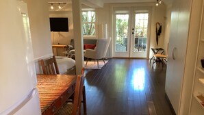 A spacious living area with a wooden dining table, a sofa, and a TV mounted on the wall. - Centrally located private studio in Chemainus (Chemainus)
