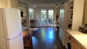 A modern kitchen with a refrigerator, wooden cabinets, and a dining area with a table and chairs. - Centrally located private studio in Chemainus (Chemainus)