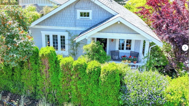 A two-story house with a porch, surrounded by lush greenery and trees. - Centrally located private studio in Chemainus (Chemainus)