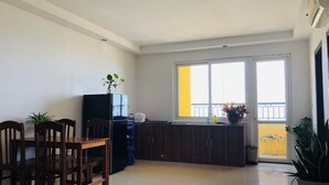 Una cuina moderna amb zona de menjador, un refrigerador negre i una planta en test sobre el taulell.