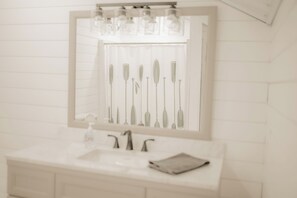 A bathroom with a white sink, a mirror, and a row of toothbrushes.