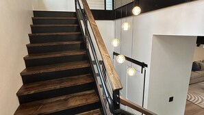 Un escalier avec des marches en bois et des rampes en métal, menant à l’étage supérieur.