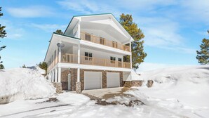 A two-story house with a balcony, stone foundation, and a garage. - Yellowstone Adventure-Island Park (Island Park)