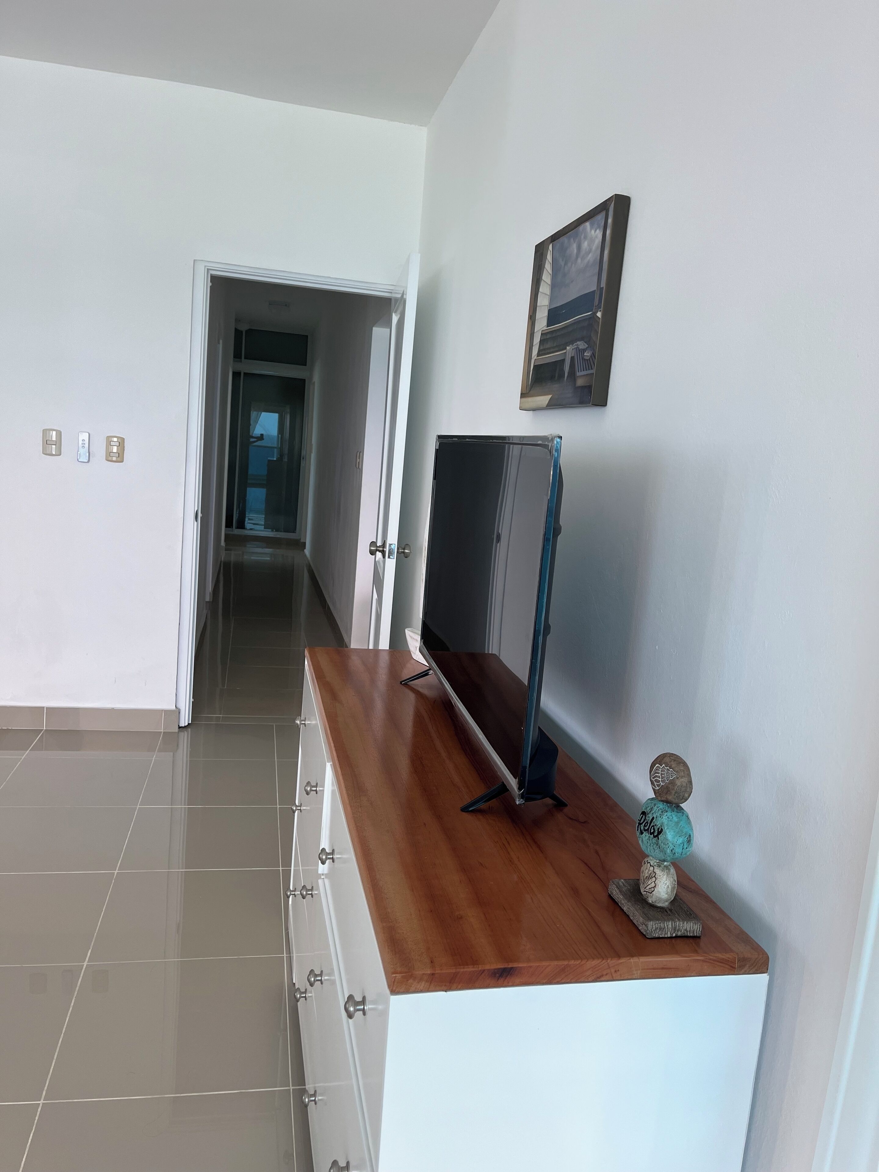 A hallway with a wooden counter, a flat-screen TV, and a decorative rock stack.