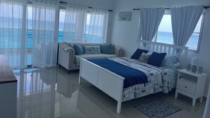 A bedroom with a bed, a sofa, a nightstand, and a view of the ocean. - Beach front apartment with spectacular views.
 (Juan Dolio)