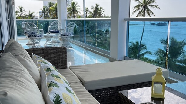 A balcony with wicker furniture, a view of the ocean, and a pool. - Beach front apartment with spectacular views.
 (Juan Dolio)