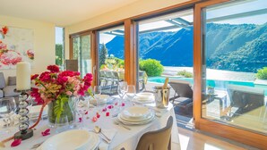 Ein Essbereich mit Tisch für vier Personen, mit Blick auf eine Berglandschaft und einen Pool.
