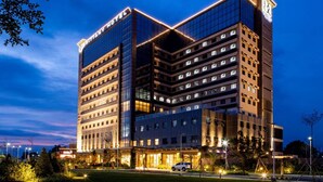 A modern hotel with multiple floors, large windows, and a well-lit facade. - Brittany Hotel Villar City (Bacoor City)