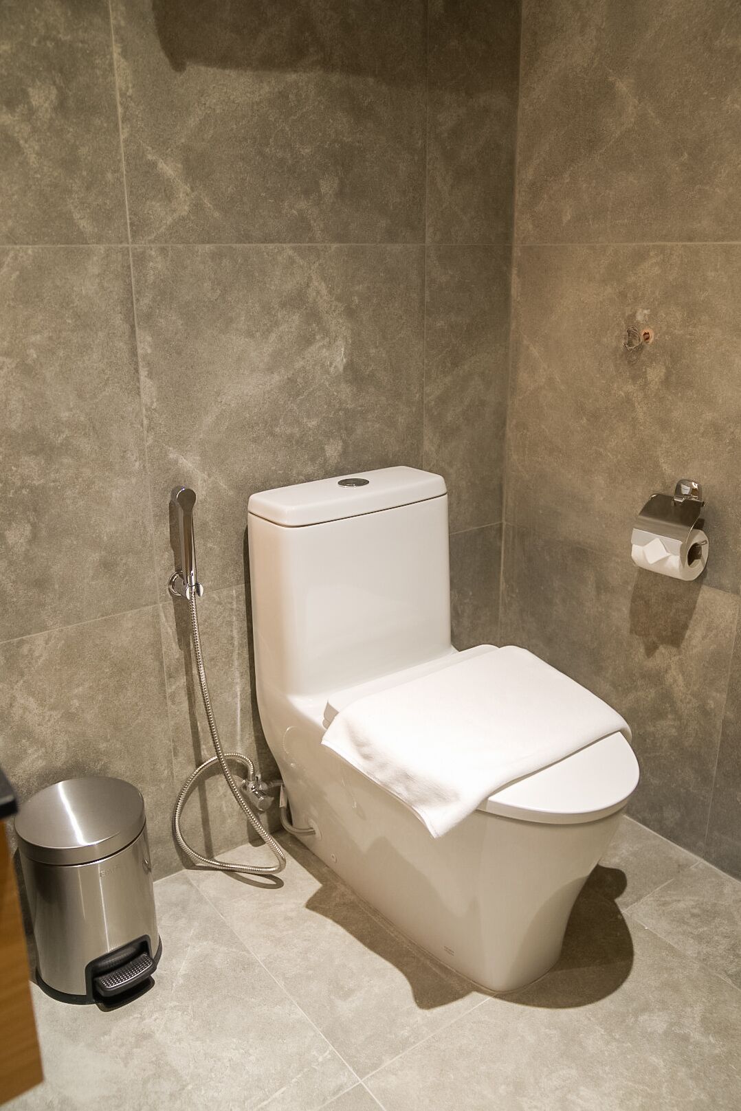 A modern bathroom with a toilet, a bidet, and a trash bin.