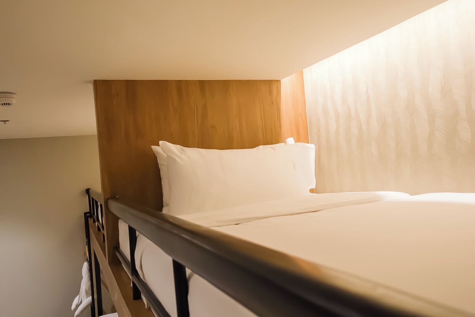 A single bed with a wooden headboard in a hotel room.