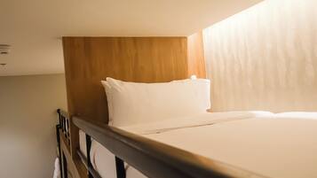 A single bed with a wooden headboard in a hotel room.