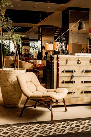 A modern interior with a leather armchair, a vintage suitcase, and a patterned floor. - Brittany Hotel Villar City (Bacoor City)