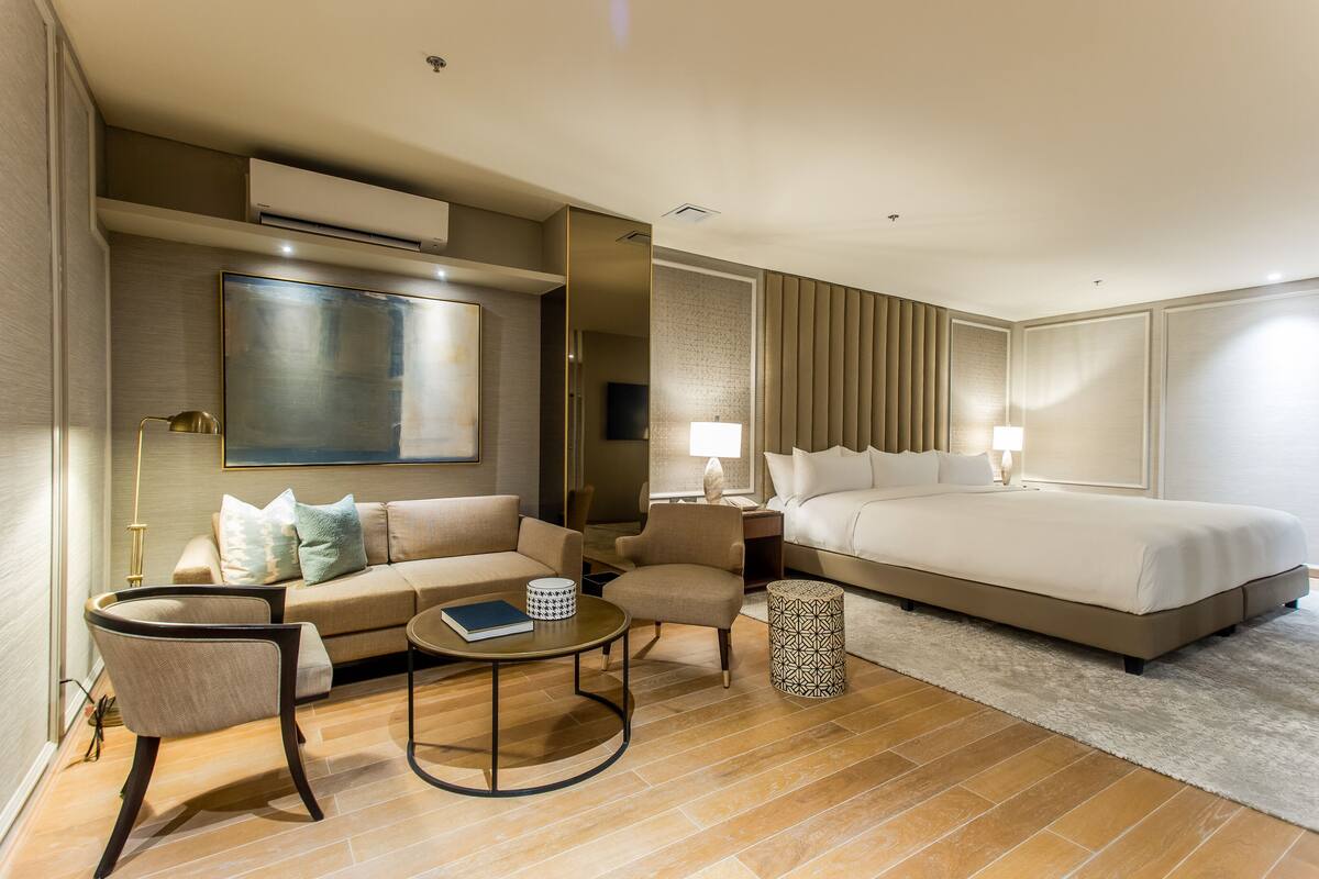 Ein Hotelzimmer mit einem großen Bett, einer Couch, einem Couchtisch und einem Fernseher.
