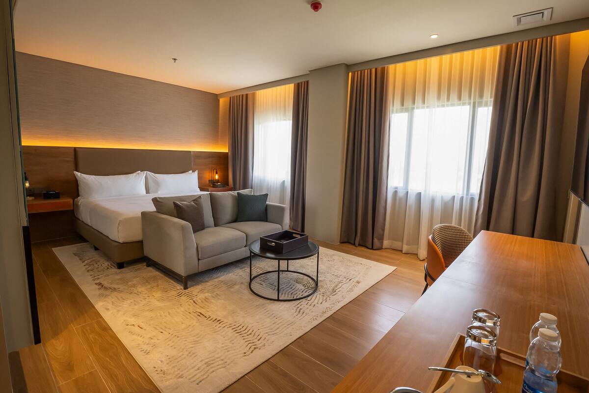 Ein modernes Hotelzimmer mit Bett, Sofa und Esstisch.