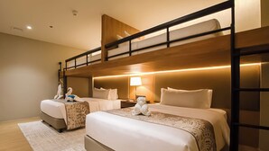 A hotel room with two beds, a wooden bunk bed, a nightstand with a lamp, and decorative swan pillows. - Brittany Hotel Villar City (Bacoor City)