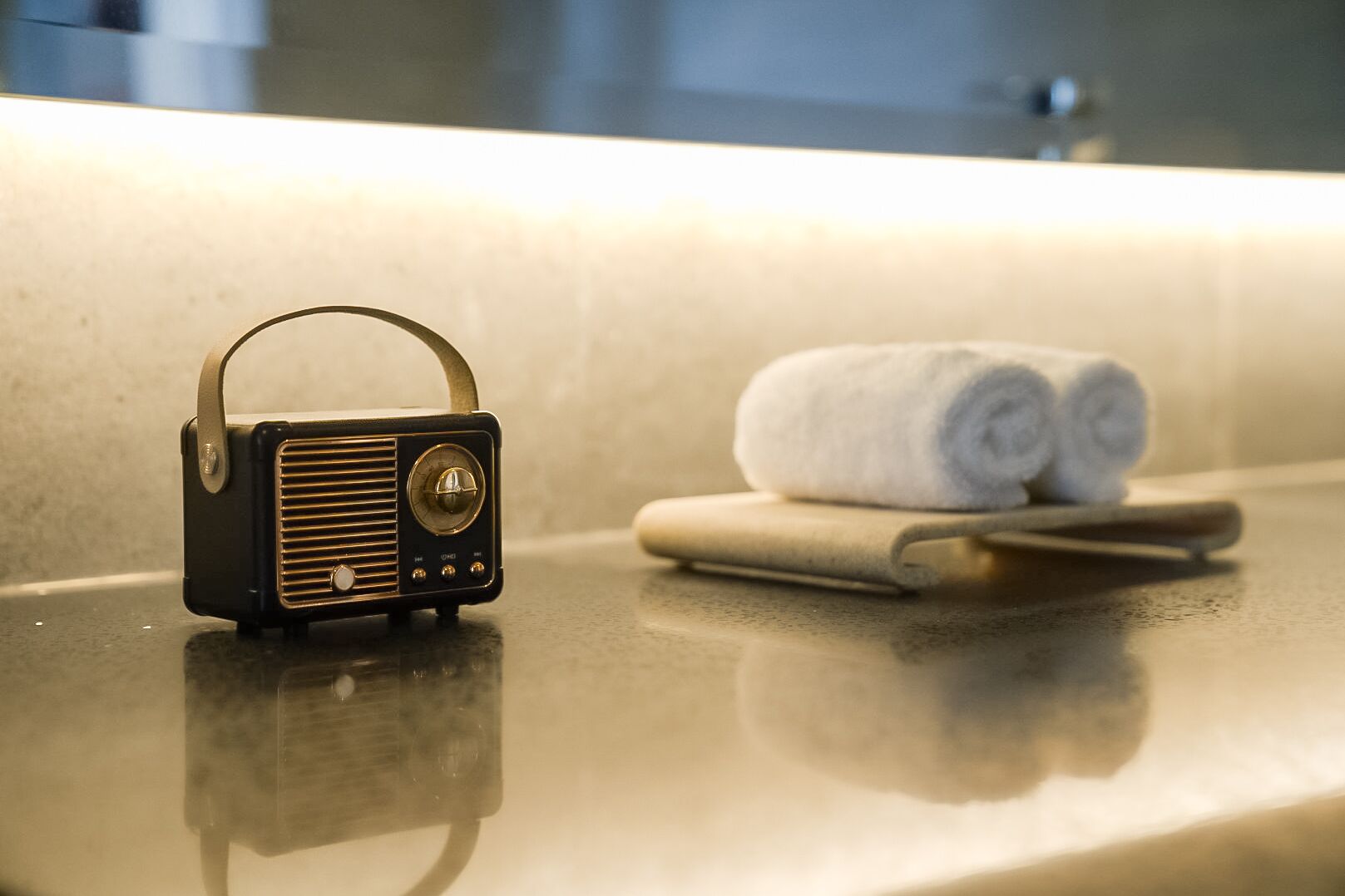 Una radio su un ripiano del bagno, con asciugamani e un rasoio.