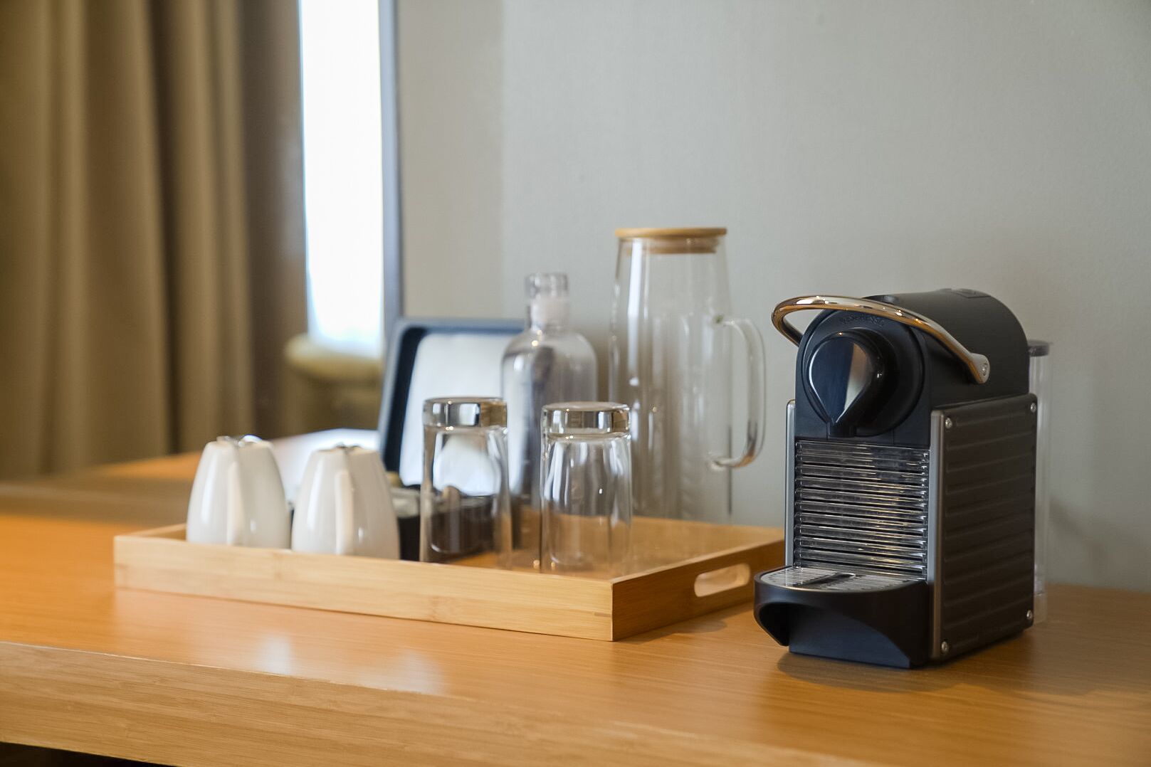 Une table en bois, sur laquelle se trouvent une machine à café, une carafe en verre et un plateau avec des salières et des poivrières.