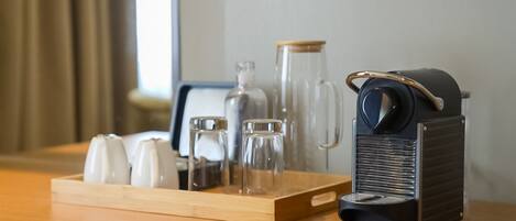 Une table en bois, sur laquelle se trouvent une machine à café, une carafe en verre et un plateau avec des salières et des poivrières.