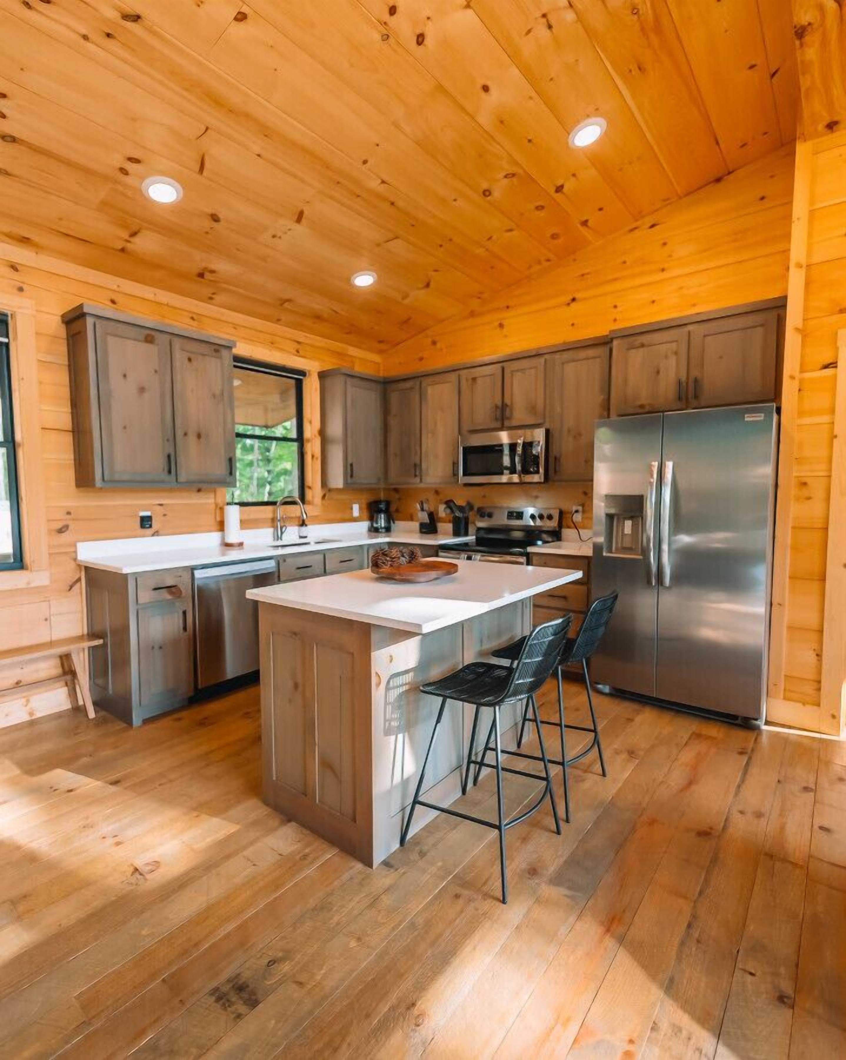 Una cocina moderna con armarios de madera, electrodomésticos de acero inoxidable y una isla central con taburetes de bar.