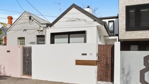 Una casa moderna con fachada blanca, puerta de garaje negra y portón marrón.