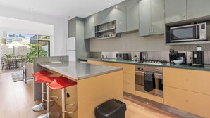 Una cocina moderna con armarios grises, electrodomésticos de acero inoxidable y taburetes rojos.