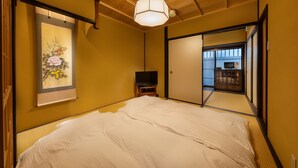 A hotel room with a bed, a television, and a painting on the wall. - Kanade Sanjusangendo (Kyoto)
