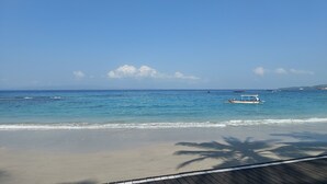 Una playa con agua azul cristalina, un bote y una cubierta de madera.