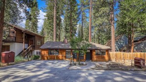 A cabin with a wooden exterior, a small porch, and a fenced yard surrounded by tall trees. - Agate Bay 3BDR, Walking Distance to the Beach! (Tahoe Vista)