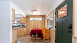 A compact kitchen with wooden cabinets, a dining table with a red tablecloth, and a green door. - Agate Bay 3BDR, Walking Distance to the Beach! (Tahoe Vista)