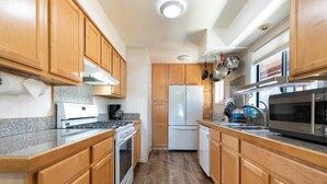 A compact kitchen with wooden cabinets, a built-in oven, a microwave, and a refrigerator. - Agate Bay 3BDR, Walking Distance to the Beach! (Tahoe Vista)